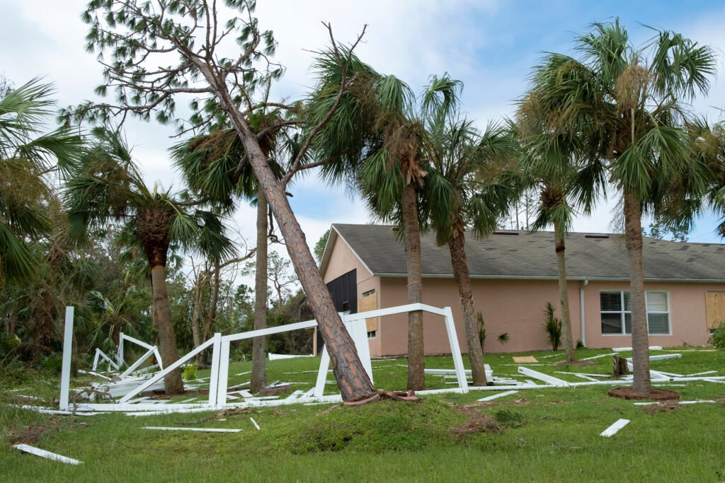 Hurricane damage to white PVC backyard fence ruined after tree debris fell down on it in Florida.